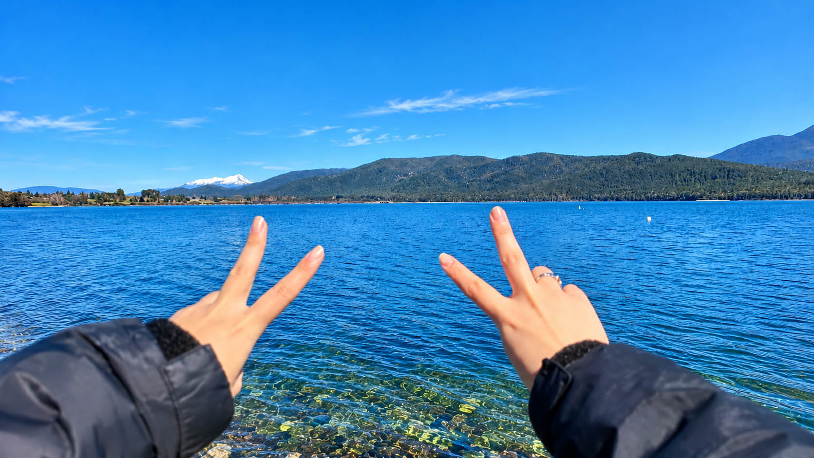 ニュージーランドの湖を前にピースをする留学生の手